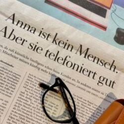 关于《安娜》的报纸文章，旁边放着眼镜和眼镜盒。