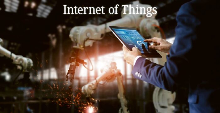 人員使用平板電腦操作工業機器人，火花四濺，字樣「物聯網」